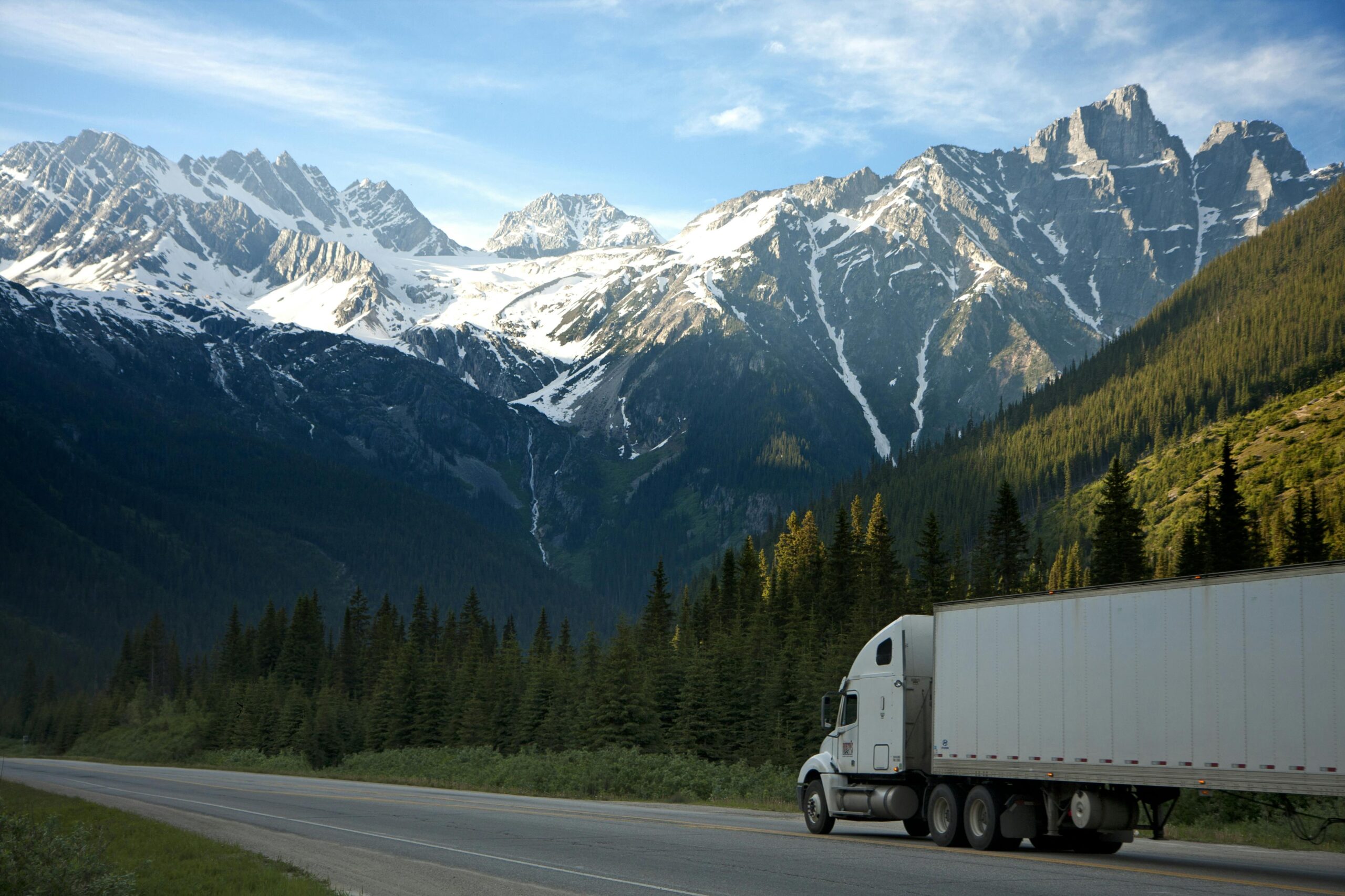 Photo of a moving truck navigating through snowy mountain terrain, with snow-covered peaks and frosted trees surrounding the road. The truck, equipped for winter conditions, moves steadily through the pristine, icy landscape, highlighting the company's capability to handle challenging and remote relocations.