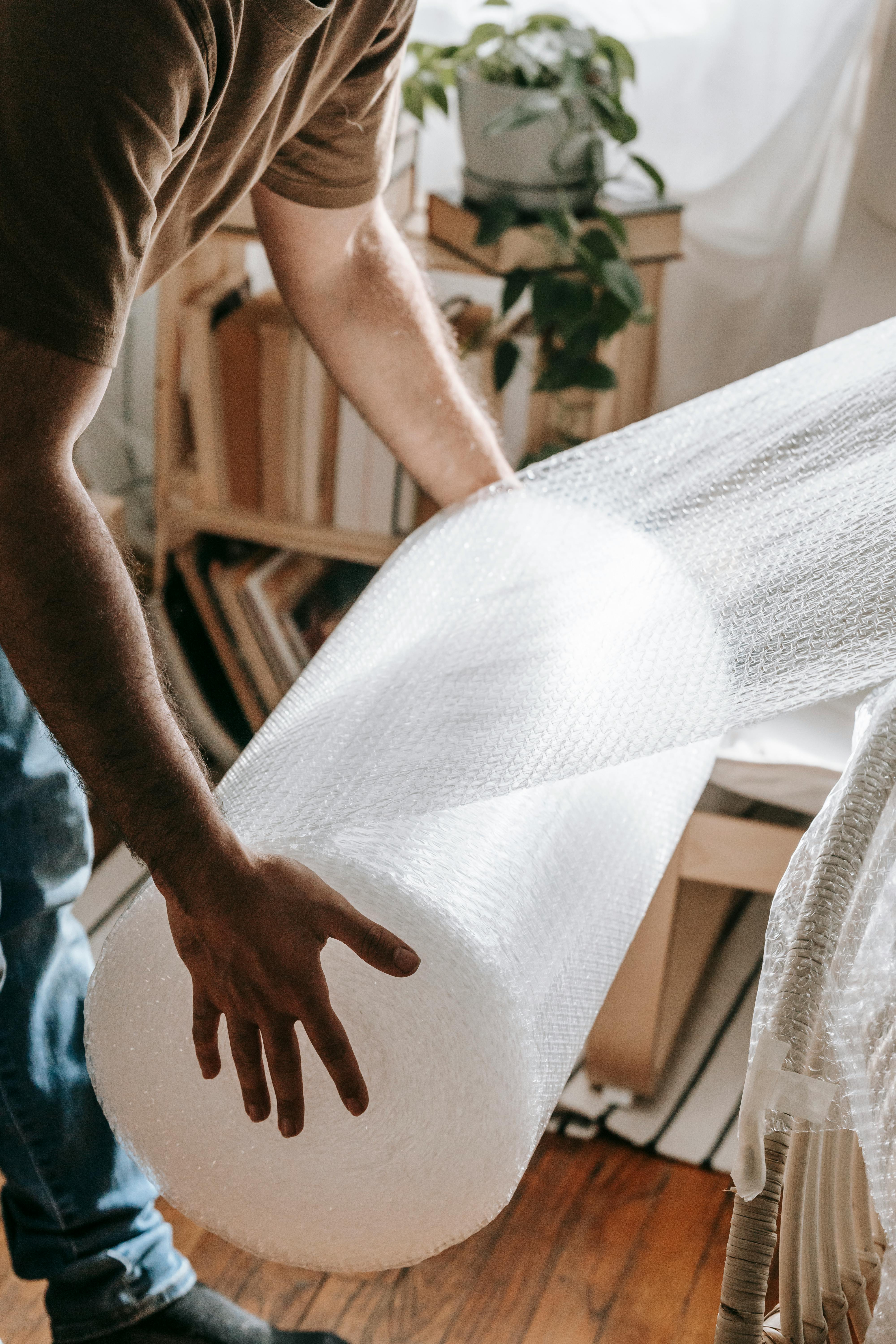 Close-up photo of a roll of bubble wrap being used for packing. The bubble wrap is partially unrolled and the bubbles are clearly visible, providing cushioning and protection for items during a move. The image highlights the essential packing materials used by a moving company to ensure safe and secure transport.