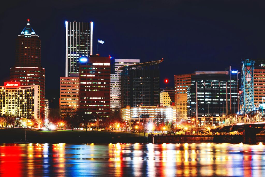 Photo of downtown Portland at night, showcasing a vibrant cityscape illuminated by streetlights and glowing skyscrapers. The bustling urban scene highlights the dynamic atmosphere and energy of the city, providing a backdrop for a moving company’s local services in the heart of Portland.