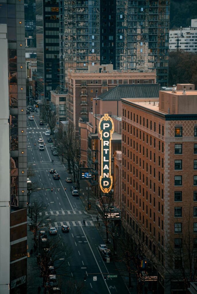 Photo of downtown Portland during the day, featuring a lively cityscape with modern skyscrapers, bustling streets, and green spaces. The bright, clear sky and active urban environment showcase the vibrant energy and dynamic character of Portland, reflecting a lively backdrop for a moving company's services in the area.