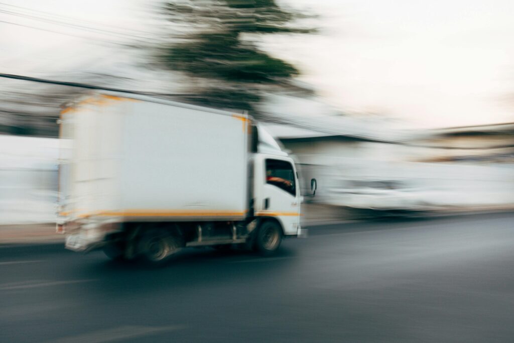 Photo of a box truck in motion, captured with a blurred effect to convey speed. The truck appears to be swiftly moving along the road, with the motion blur emphasizing its efficiency and quick service, ideal for a moving company that prides itself on fast and reliable transportation.