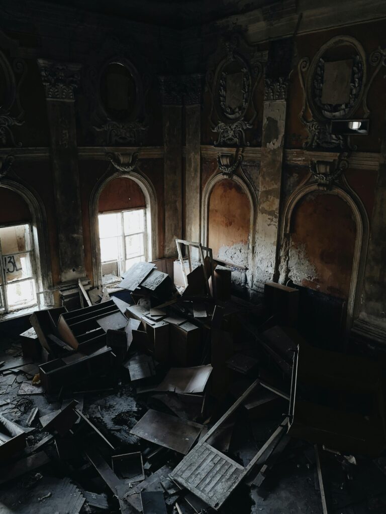 Photo of burnt scrap metal debris from a fire in a building. The metal pieces are charred and twisted, scattered among remnants of the fire damage. The image highlights the extent of damage and the need for careful removal and disposal by a specialized junk hauling service.